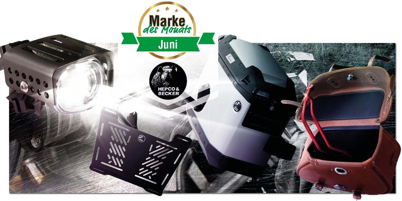 Spannende Komposition von Hepco & Becker Produkten, welche von einem Motorrad-Zusatzscheinwerfer angestrahlt werden. Darauf das "Marke des Monats"-Logo" und das "Hepco & Becker"-Logo"