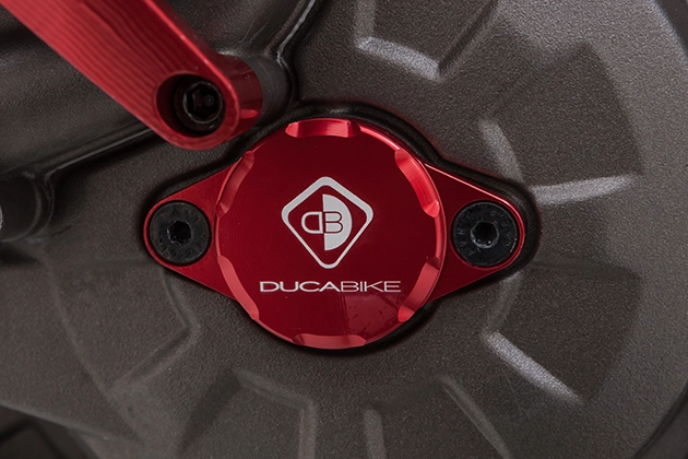 Close-up view of a red anodised ignition control cover with the inscription "Ducabike"