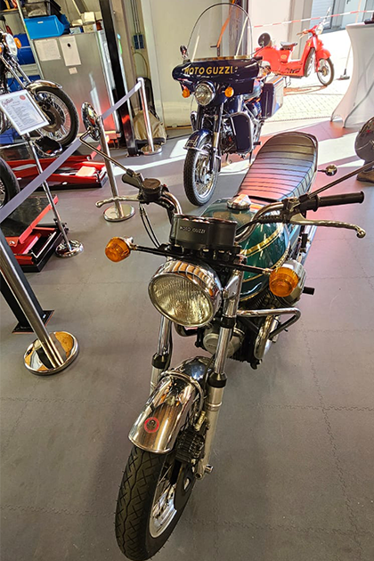 Vista frontal de una Motot Guzzi verde y otra azul oscuro reconstruidas, más antiguas, de Doc Jensen, que están una detrás de otra en una sala.