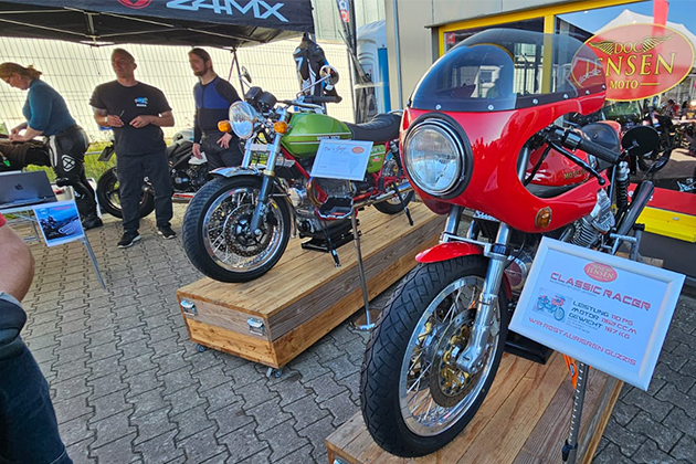 2 modelos antiguos convertidos de Moto Guuzi se exponen en plataformas de madera delante de la tienda