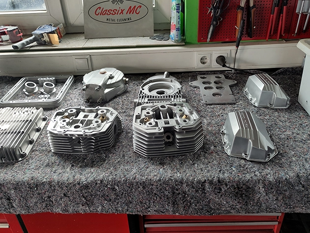 Cylinder heads, cylinder blocks, valve covers and other components are on a workbench.