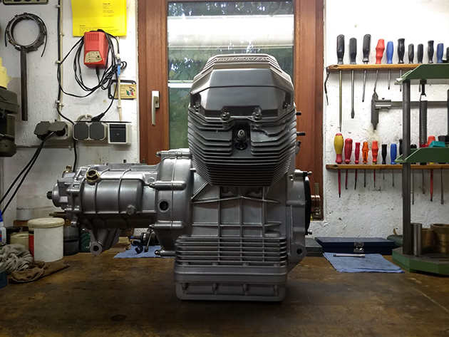 Cylinder heads, cylinder blocks, valve covers and other components are on a workbench.