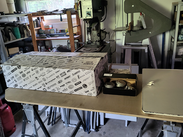 Several freshly restored Moto Guzzi engine parts are lying on a workbench. The parts include cylinder heads, cylinder blocks, valve covers and other components in perfect condition.